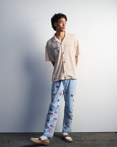 Model wearing Ryoko Rain ivory pleated button-up with butterfly embroidered jeans