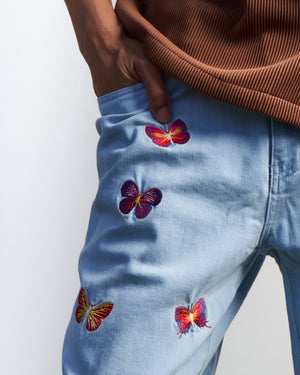 Close-up photo of small embroidered butterflies near right front pocket. Light blue washed denim