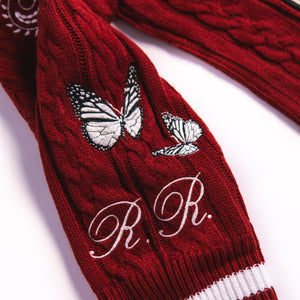 Maroon cable-knit cardigan sleeve with monogram R.R. initials and butterfly embroidery