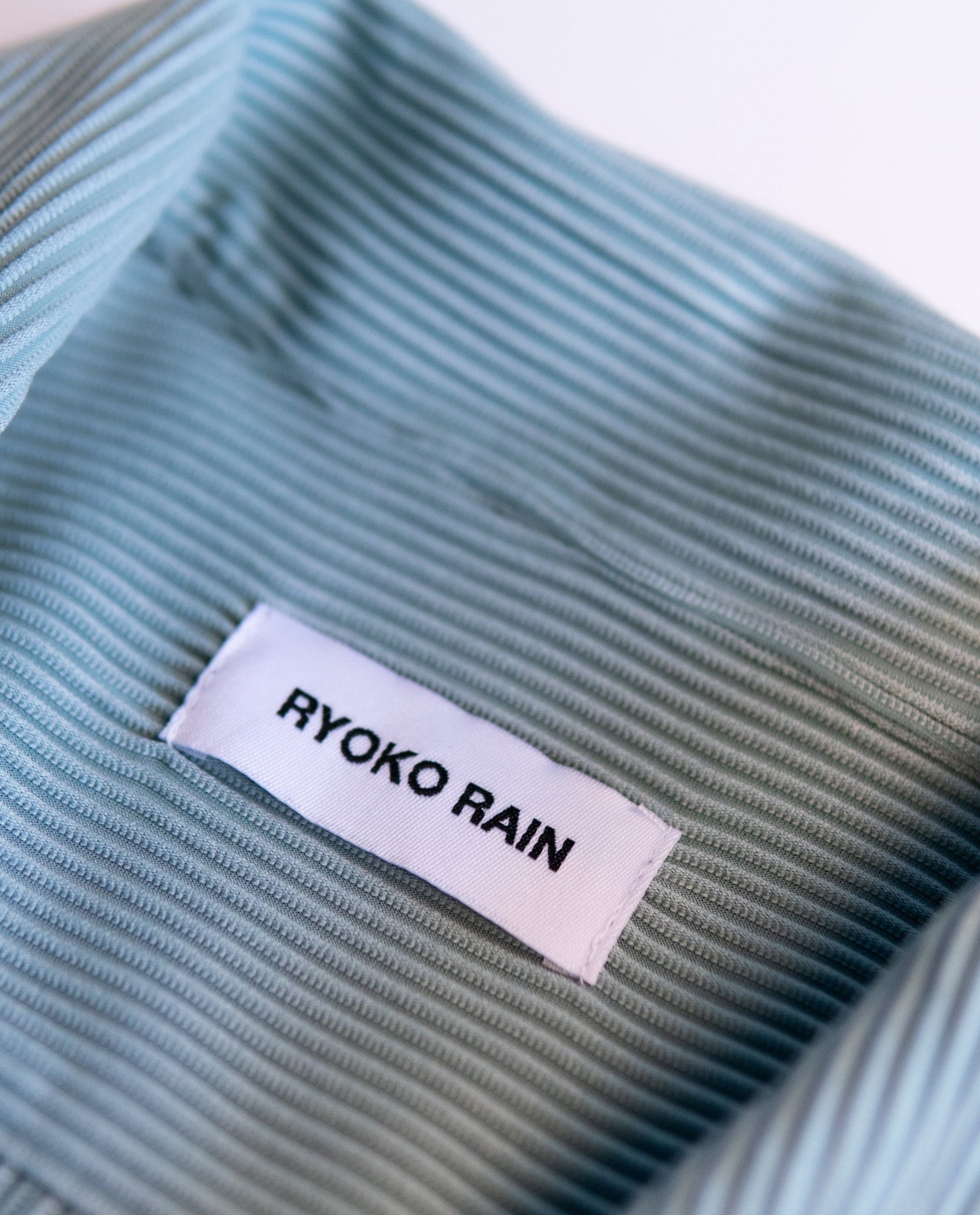 Ryoko Rain Ice pleated button-up shirt. Close-up photo of collar details with Ryoko Rain clothing tag